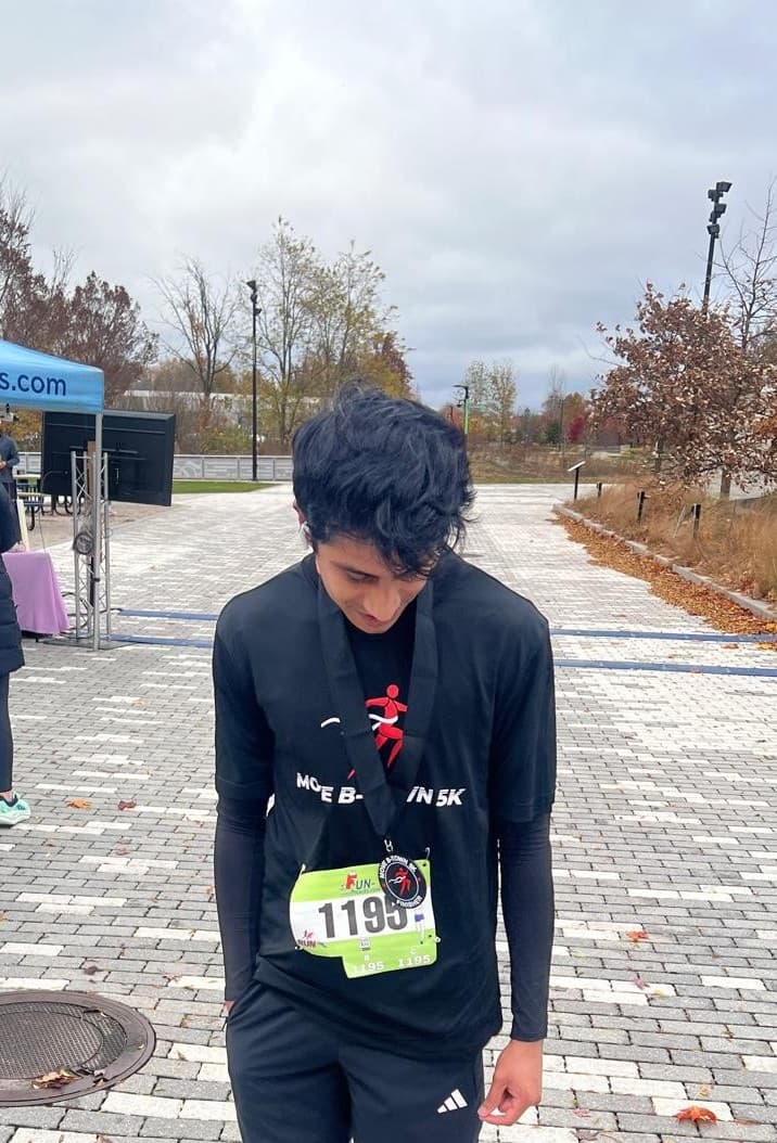 Atharva after a run, wearing a race bib and medal